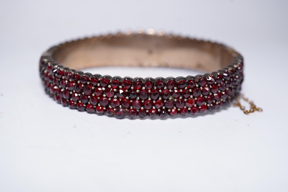 A suite of garnet and paste jewellery, comprising: a brooch, 5cm diameter; a bangle, inner circumference 16cm; two rings, sizes I and M; a pair of earrings, and a single earring, each set with rose-cut garnets; and a pai